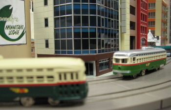 Bachmann N scale PCCs on an EasyTrolley layout. Tomix track and street, pre-made buildings by Kato, Tomix and Model Power/Pola.